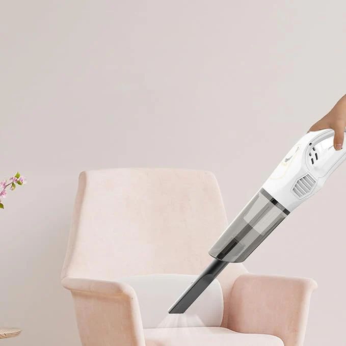 Handheld vacuum cleaner cleaning a chair against a light background